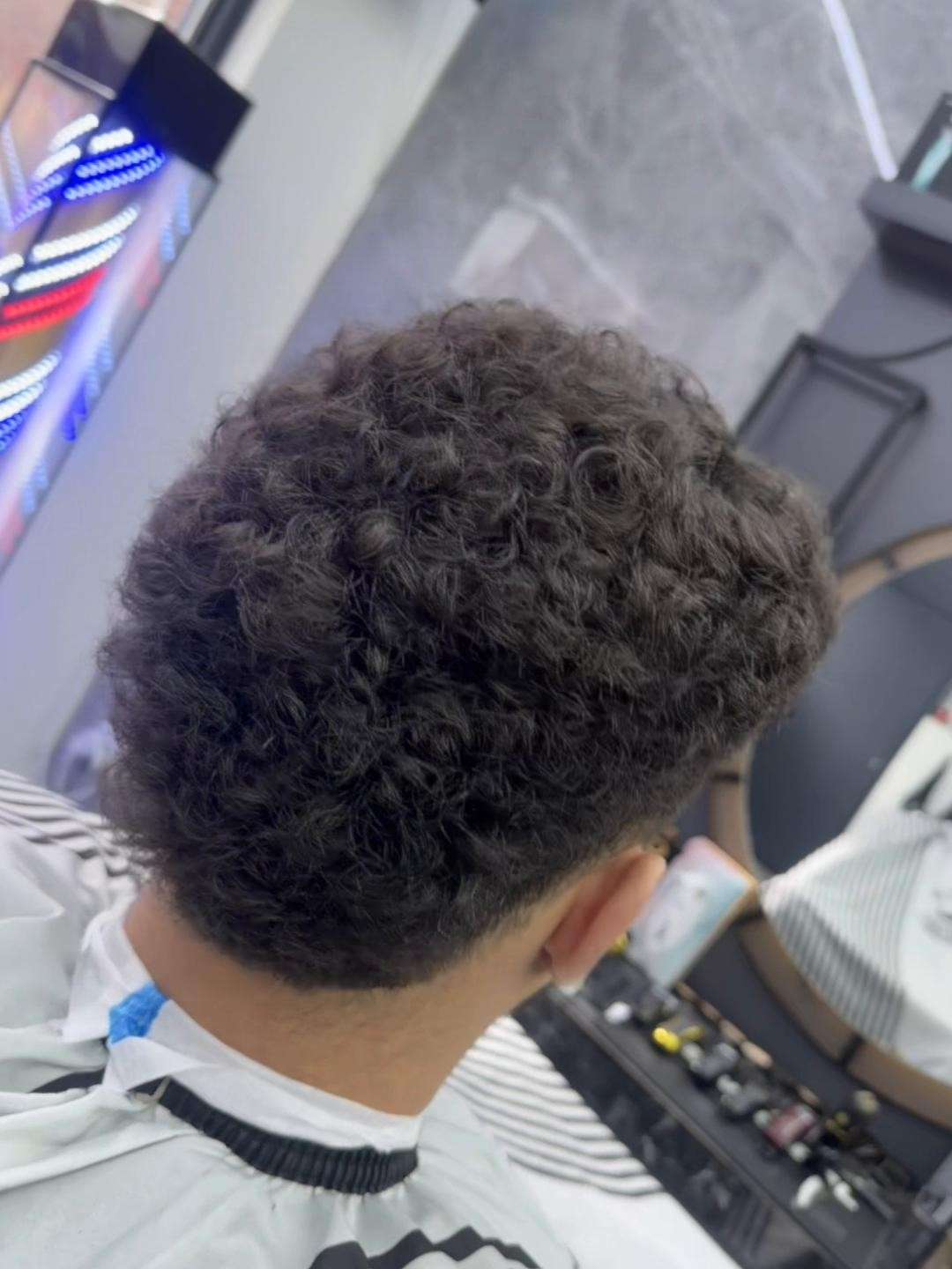 Krullen bovenop met een taper in de nek, van achteren gezien, bij City Style Barbershop